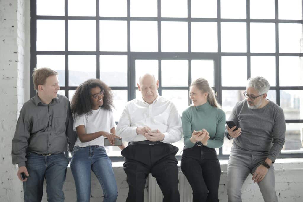 a diverse group of professionals collaborating and using mobile devices, representing teamwork in a sales partner program