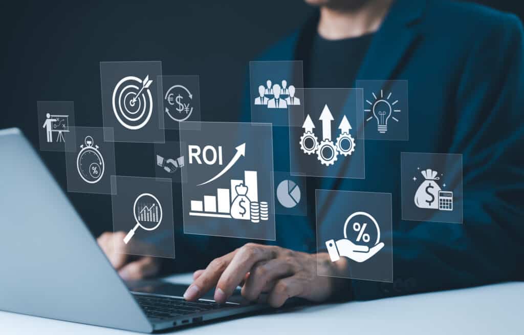 Businessman working on a laptop with various digital icons representing ROI, financial strategies, sales, and hiring efficiency